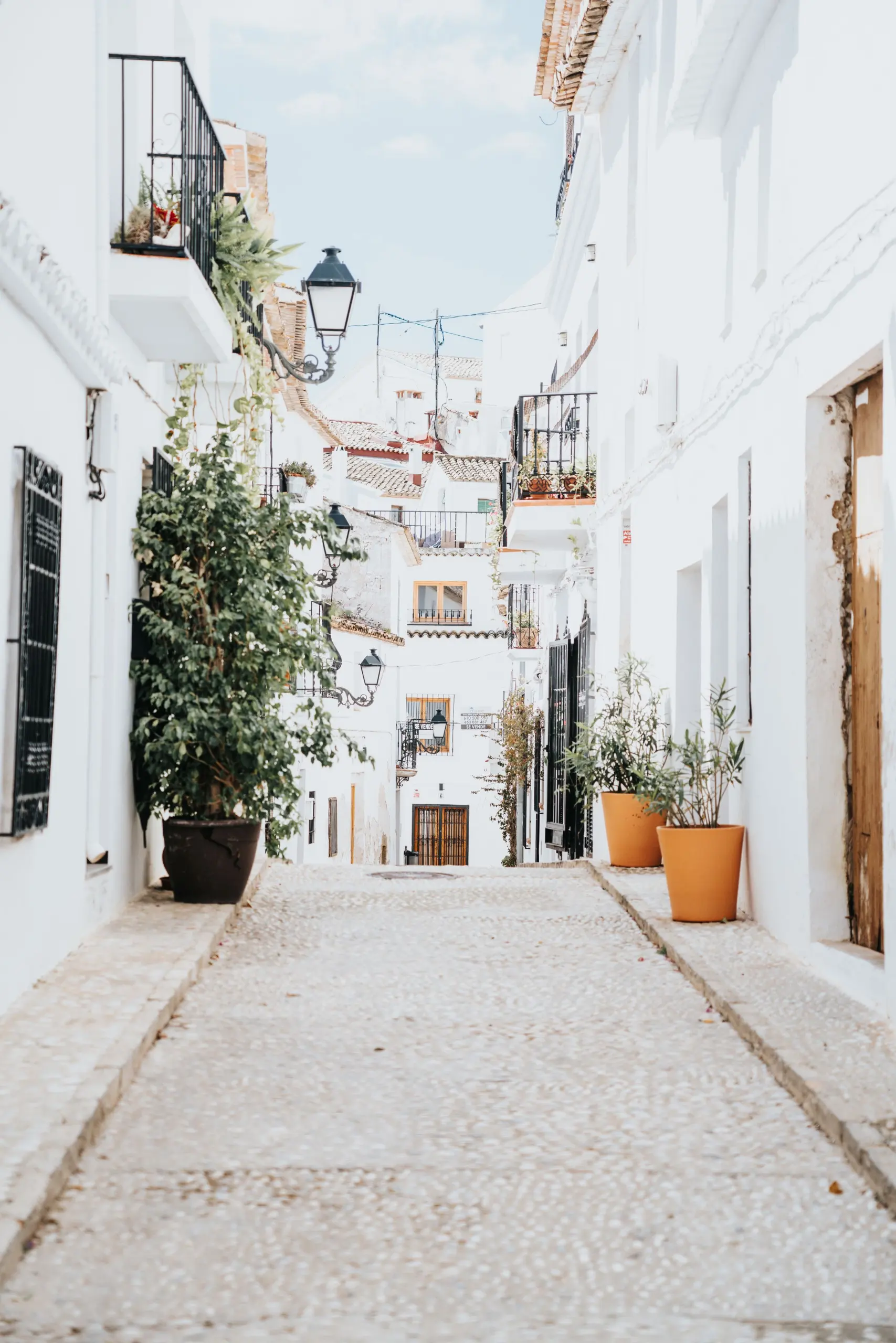 A quiet cobbled lane between whitewashed houses with iron balconies